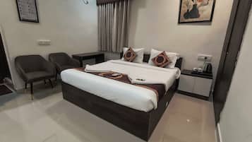 Una habitación de hotel con una cama, una silla, una mesita de noche y un cuadro en la pared.
