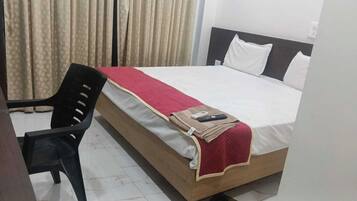 A hotel room with a bed, a chair, and a curtain.