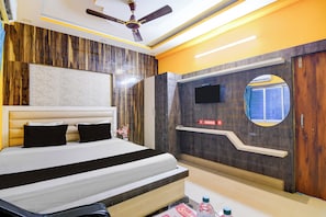 Un dormitorio moderno con una cama grande, ventilador de techo, televisor montado y una pared decorativa de madera.