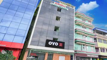 Un edificio de varios pisos con un letrero llamativo de 'OYO' en la fachada, que indica un hotel o alojamiento.