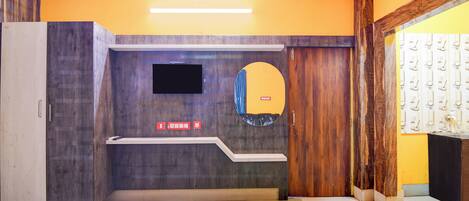 A hotel room with a bed, a flat-screen TV mounted on the wall, a mirror, and a wooden door.