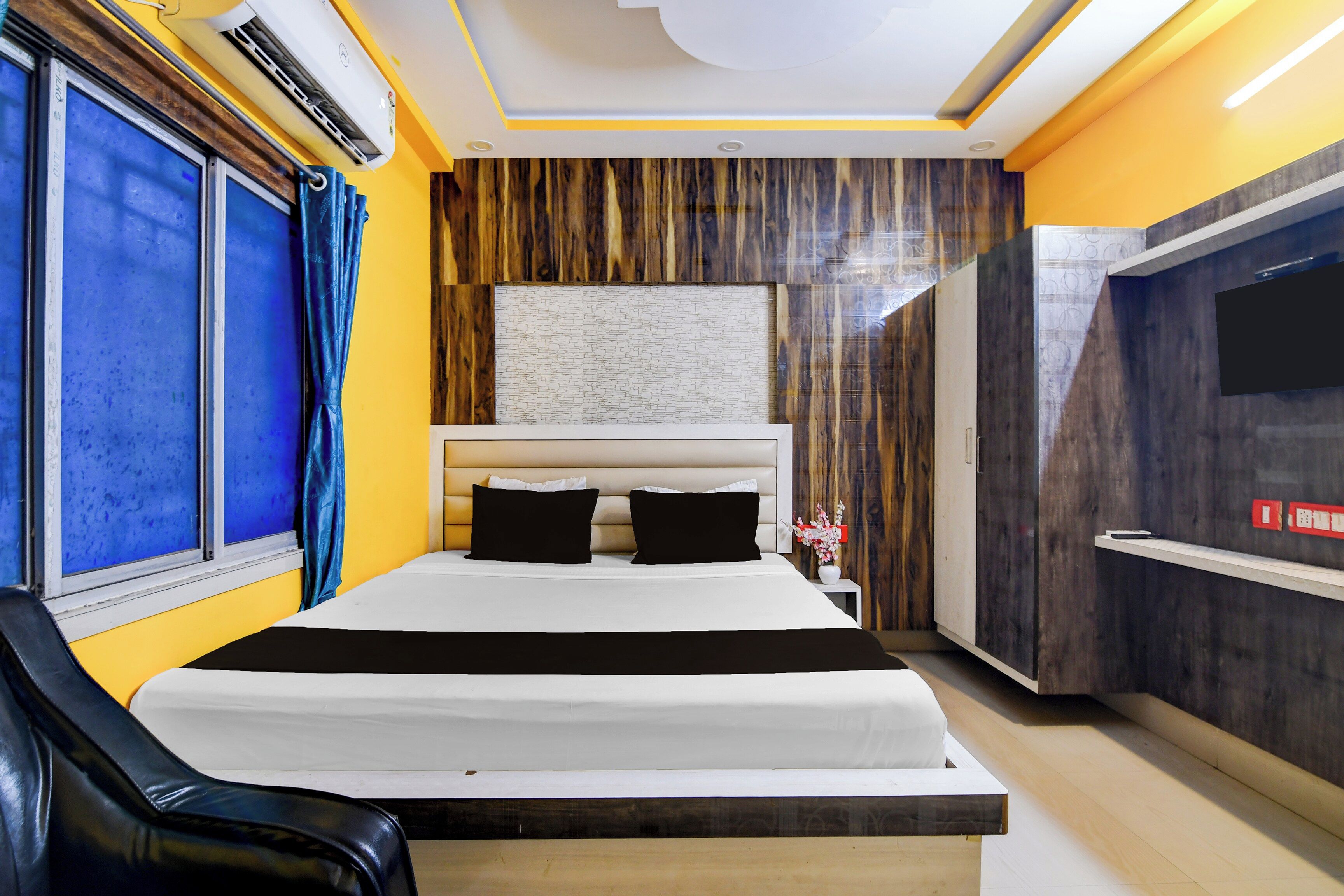 Habitación de hotel con cama, televisión y ventana con cortinas.