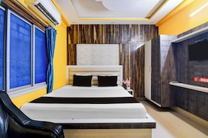 Habitación de hotel con cama, televisión y ventana con cortinas.