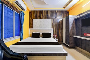 Habitación de hotel con cama, televisión y ventana con cortinas.