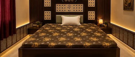 A modern bedroom with a large bed, a headboard with decorative panels, a bedside table with a lamp, and a wall-mounted artwork.