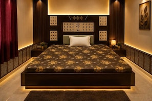 Ein modernes Schlafzimmer mit einem großen Bett, einem Kopfteil mit dekorativen Verzierungen, einem Nachttisch mit Lampe sowie einem an der Wand hängenden Kunstwerk.