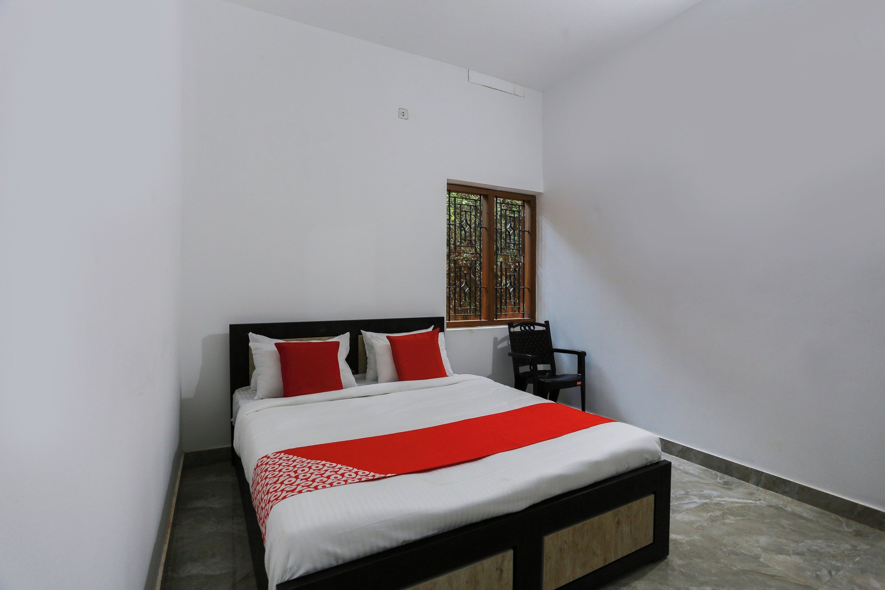 A bedroom with a bed, a chair, and a window.