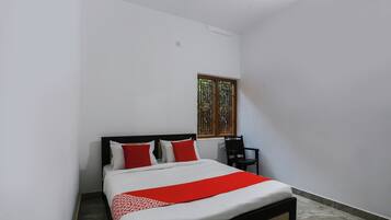 A bedroom with a bed, a chair, and a window.