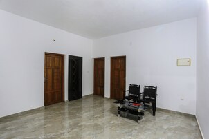 Una habitación con suelo de mármol, dos puertas de madera y dos sillas negras.