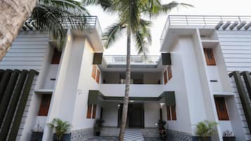 A modern building with a central entrance, potted plants, and a palm tree.
