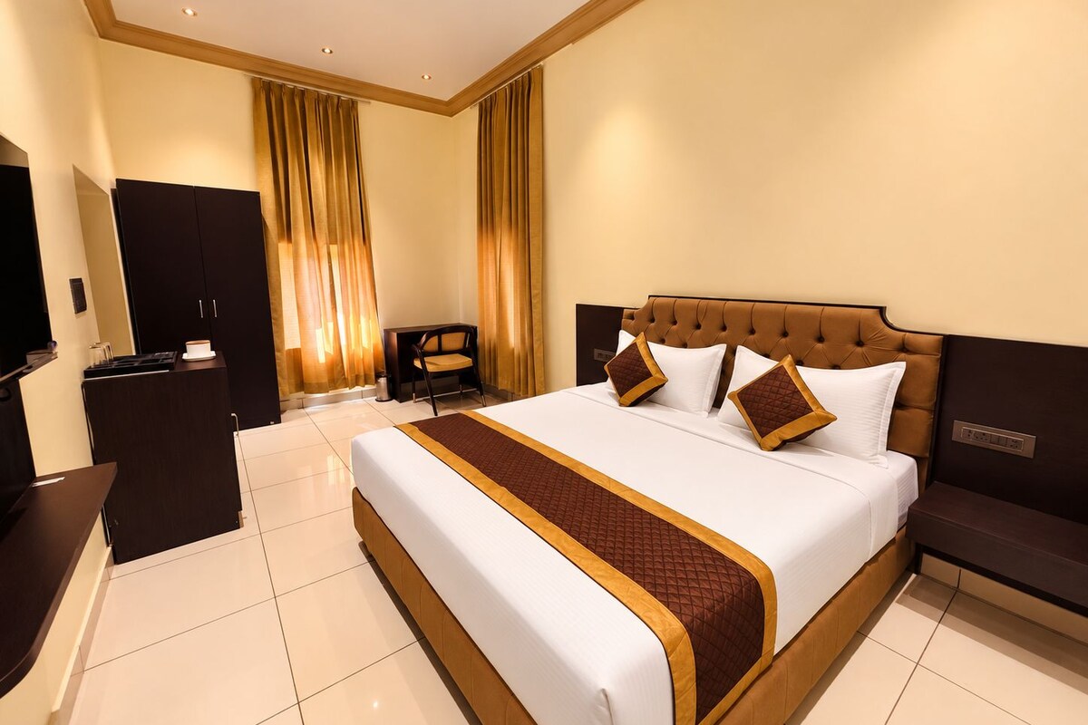 Une chambre d’hôtel avec un grand lit, un bureau, une chaise et un téléviseur.