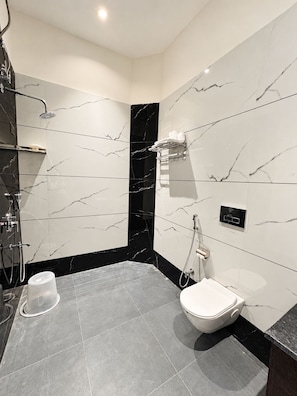 Une salle de bain moderne équipée d’une douche, de toilettes et d’un porte-serviettes.