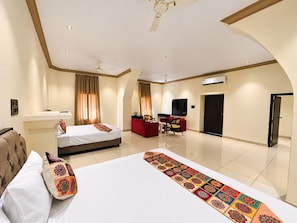 Une chambre d’hôtel avec deux lits, un bureau, une télévision et une porte.