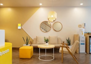 Un moderno vestíbulo de hotel con un sofá, espejos redondos, una mesita y un detalle en color amarillo.