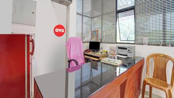 A room with a desk, a chair, a red cabinet, and a window with blinds.