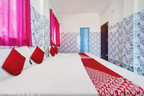 A hotel room with a large bed, red pillows, and patterned wallpaper. - Hotel O Sri Sakthi Residency (Kanyakumari)