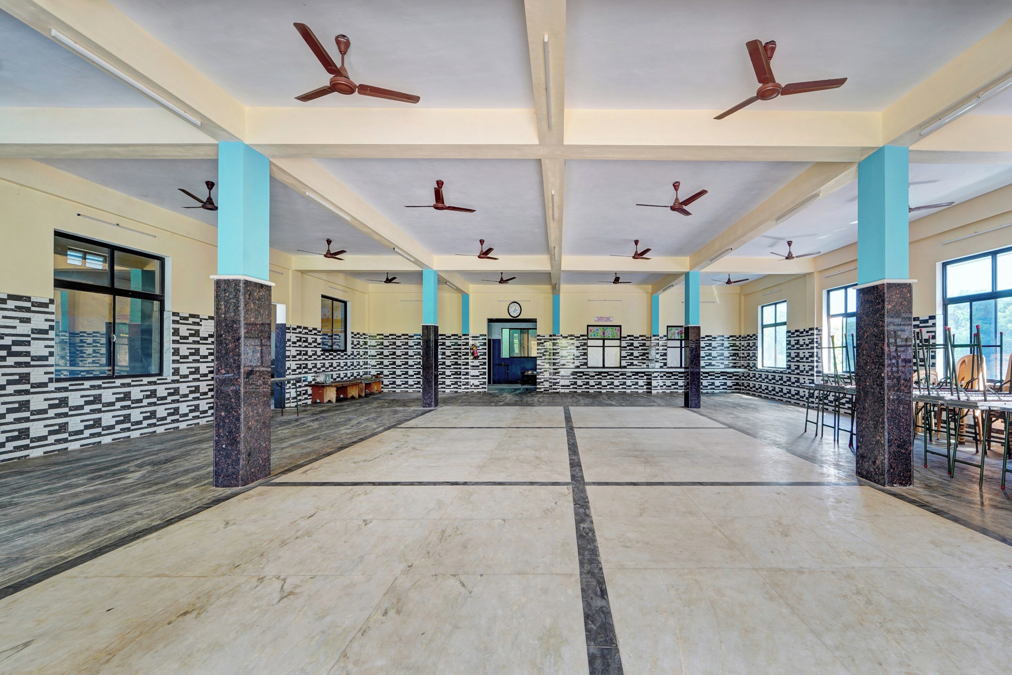 A spacious hall with multiple ceiling fans, a clock, and patterned walls.
