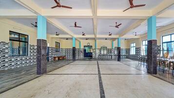 A spacious hall with multiple ceiling fans, a clock, and patterned walls.