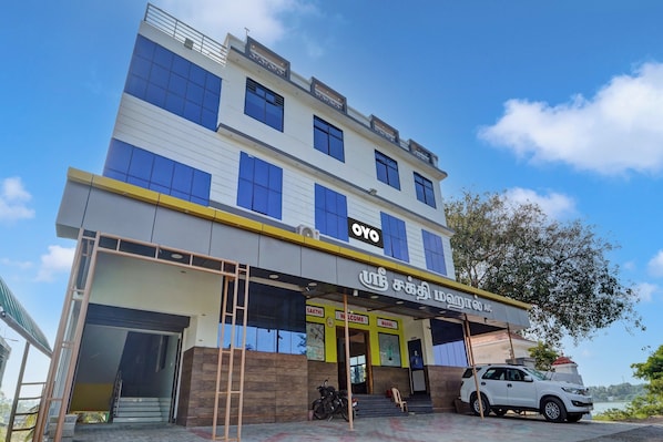 A multi-story building with a prominent OYO brand sign, a motorcycle parked in front, and a vehicle parked to the right. - Hotel O Sri Sakthi Residency (Kanyakumari)