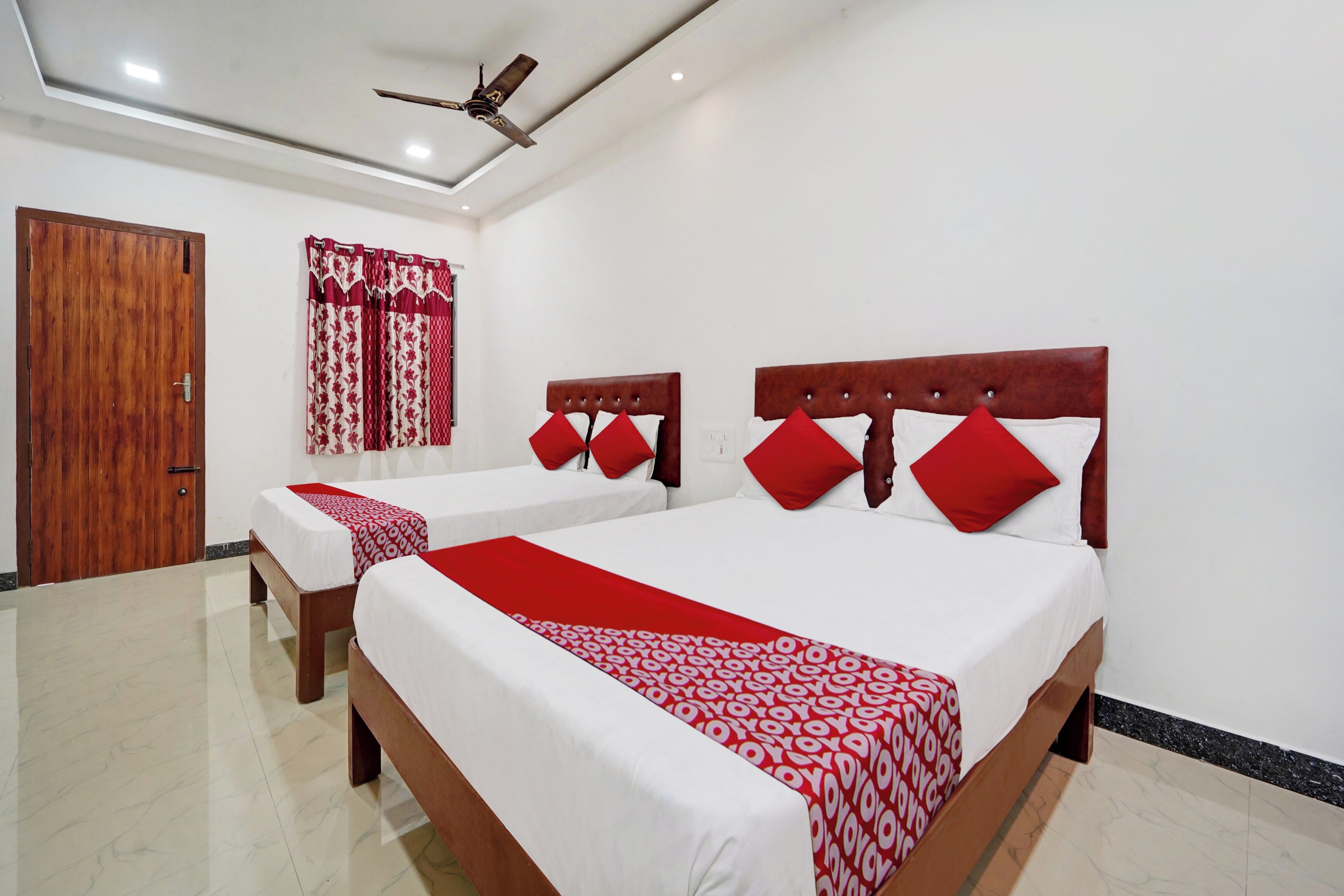 A hotel room with two beds, a ceiling fan, and a wooden door.