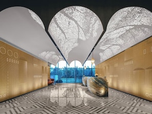 A modern interior with a reception desk, patterned flooring, and large windows. - Hotel Indigo Yantai Golden Coast by IHG (Yantai)