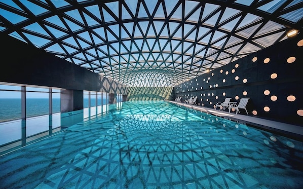 A modern infinity pool with a geometric ceiling design, surrounded by walls with circular light fixtures. - Hotel Indigo Yantai Golden Coast by IHG (Yantai)