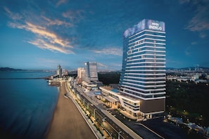 A modern hotel with multiple floors, a prominent sign, and a beachfront location. - Hotel Indigo Yantai Golden Coast by IHG (Yantai)