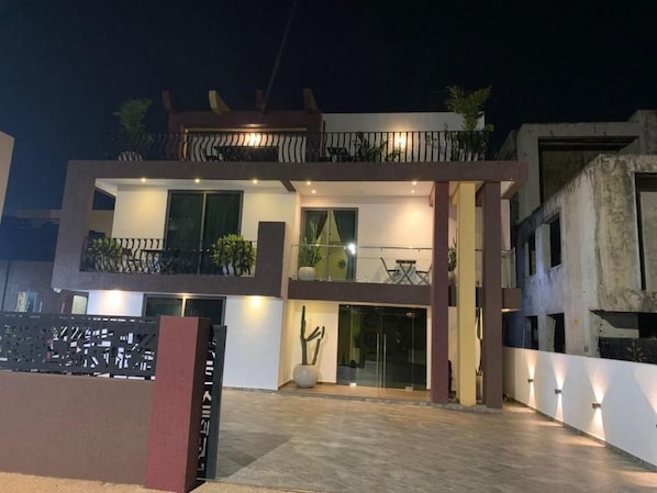 A modern two-story building with a balcony, a glass door entrance, and a well-lit interior. - Ridge Condos Hotel (Kumasi)