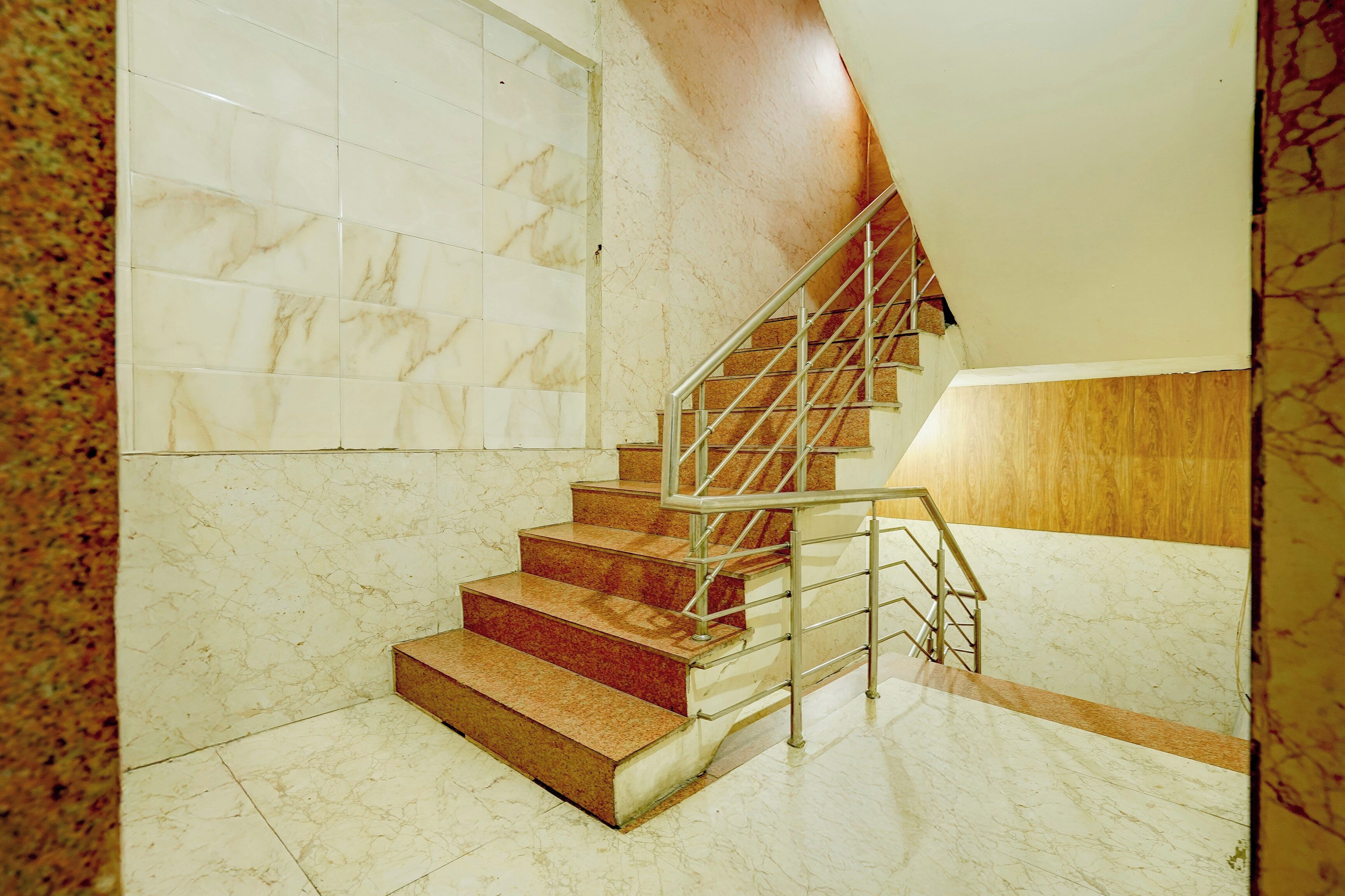 Una escalera con paredes de mármol y barandilla de madera.