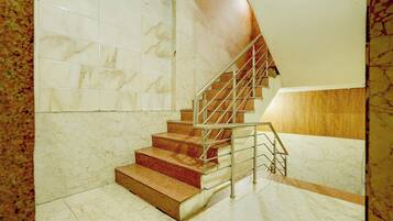 Una escalera con paredes de mármol y barandilla de madera.