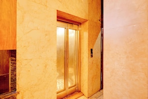 Un pasillo con una pared de mármol y una puerta de madera que da a una habitación.