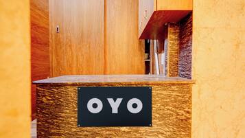 Una recepción con un cartel que dice 'OYO' y una puerta de madera al fondo.