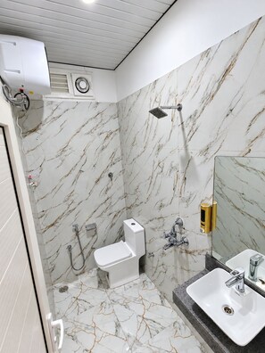 A bathroom with a toilet, sink, shower, and marble walls. - Ramaya Palace (Varanasi)