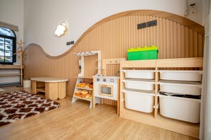 A children's playroom with a wooden curved wall, a small kitchen area with a stove, and storage bins. - Phuttho Pool Villa Khaokho (Khao Kho District)