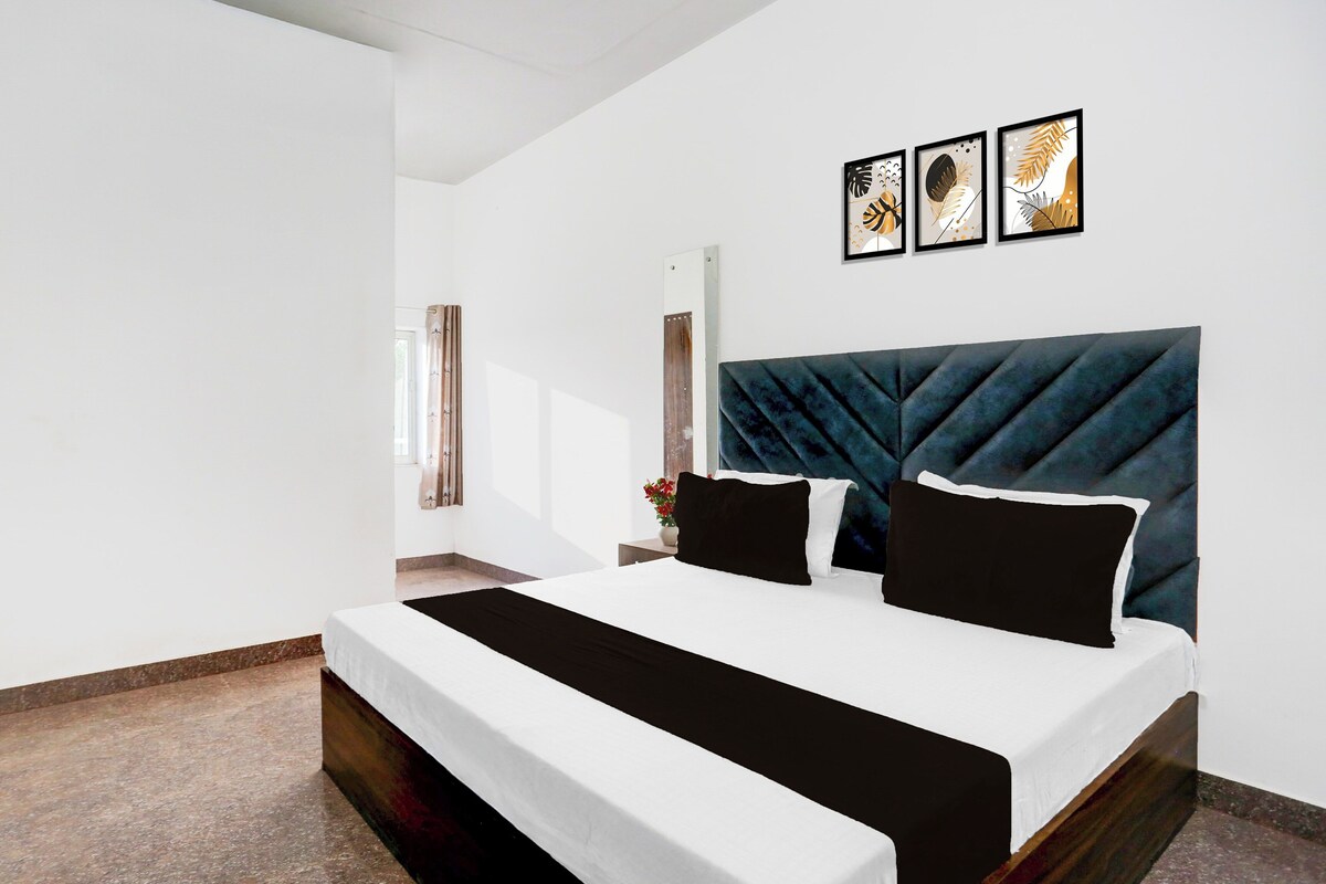 Une chambre à coucher moderne avec un grand lit, une tête de lit sombre et trois œuvres d’art encadrées accrochées au mur.