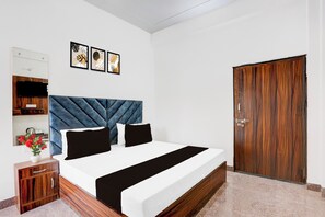 Une chambre à coucher avec un lit, une armoire en bois, un miroir et trois tableaux encadrés accrochés au mur.