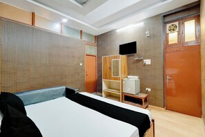 A hotel room with a bed, a television, a wardrobe, and a small table. - HOTEL O TIRUPATI (Meerut)