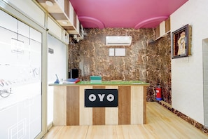 A reception desk with a sign reading 'OYO', a wall-mounted air conditioner, and a fire extinguisher. - HOTEL O TIRUPATI (Meerut)