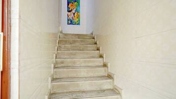 Una escalera conduce a una habitación con un colorido cuadro religioso en la pared.