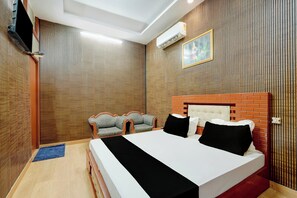 A hotel room with a large bed, a TV mounted on the wall, and a window with blinds. - HOTEL O TIRUPATI (Meerut)