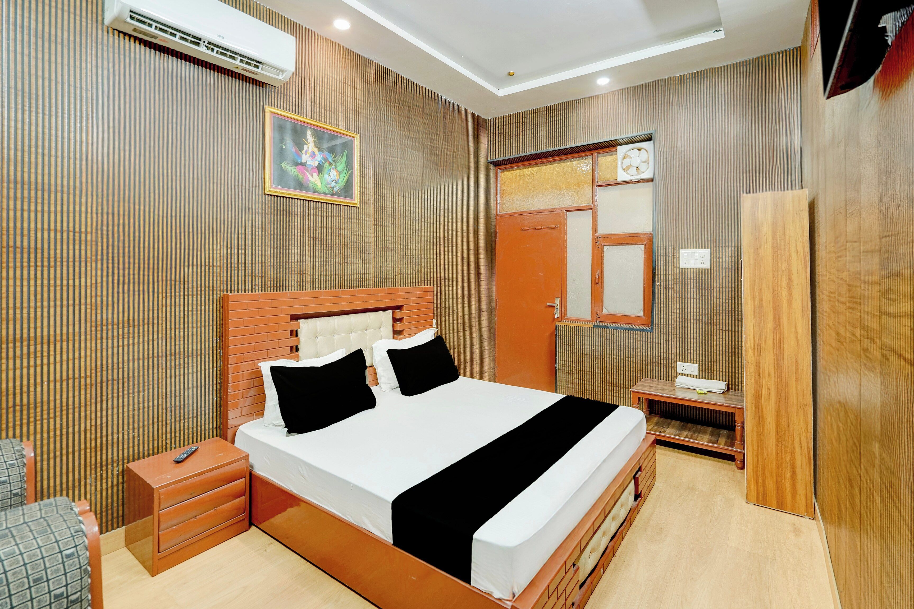 Una habitación de hotel con cama, mesita de noche y espejo.