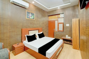 A hotel room with a bed, bedside table, and a mirror.