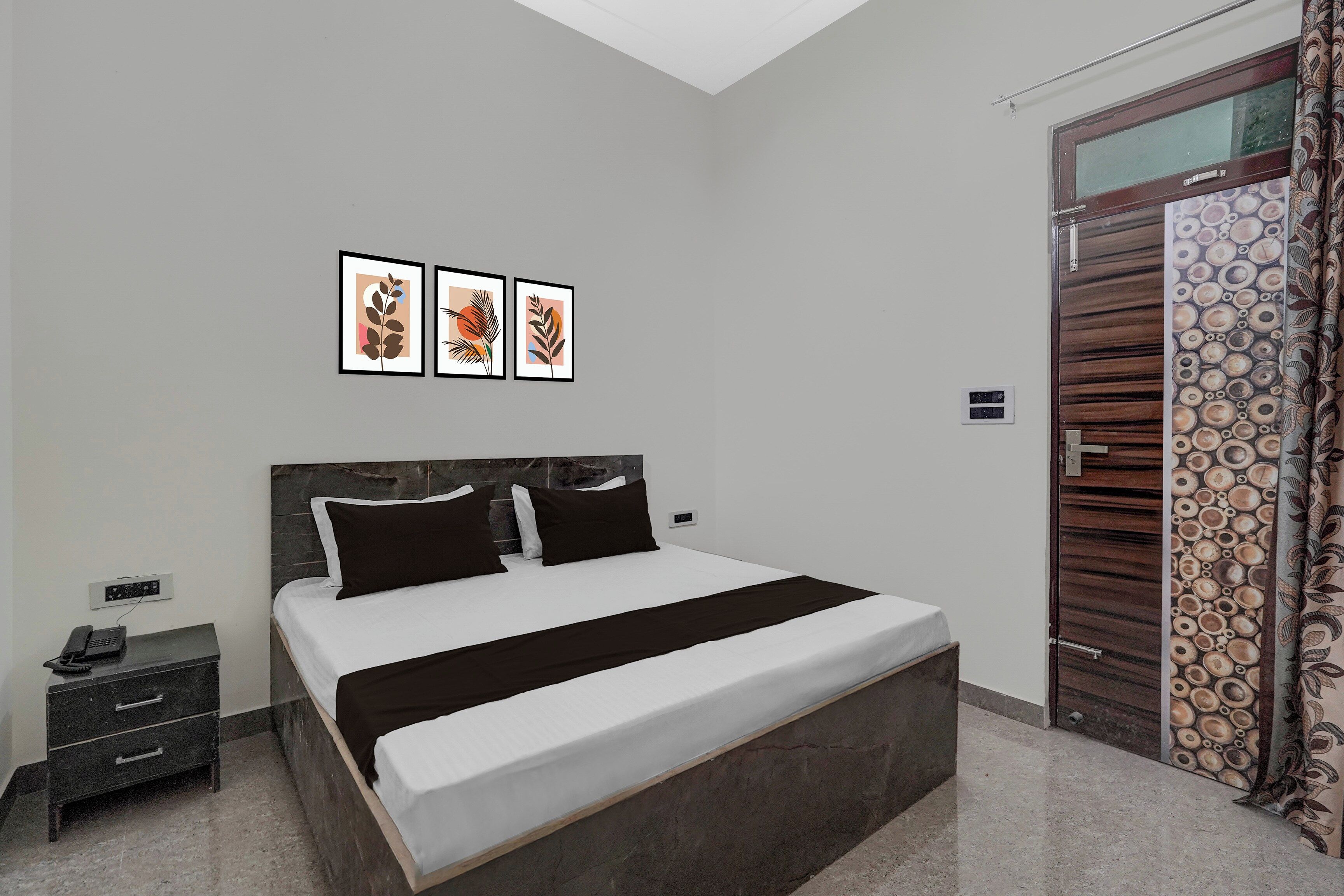 A bedroom with a bed, bedside tables, a phone, and artwork on the wall.