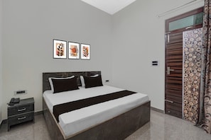 A bedroom with a bed, bedside tables, a phone, and artwork on the wall. - Hotel O Choudhary Hotal & Resort (Meerut)
