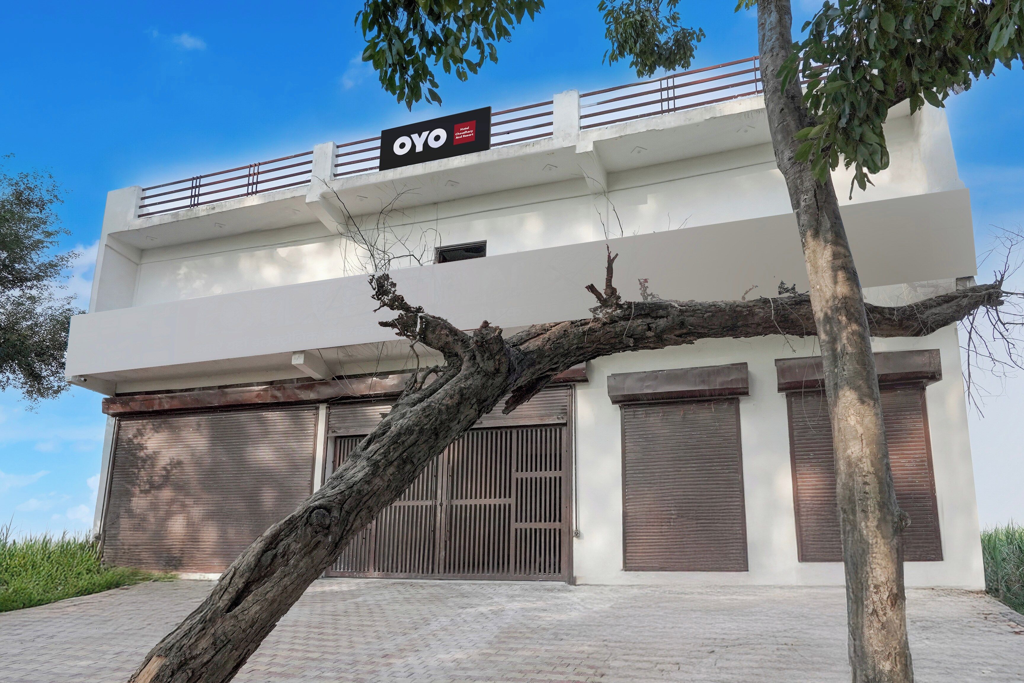 A building with a sign reading 'OYO Hotel & Resort' and a large tree in front.