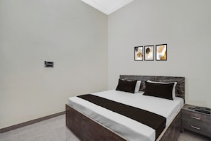 A bedroom with a bed, bedside tables, and a wall-mounted light fixture. - Hotel O Choudhary Hotal & Resort (Meerut)