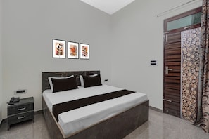 A bedroom with a bed, bedside tables, a phone, and framed artwork on the wall. - Hotel O Choudhary Hotal & Resort (Meerut)