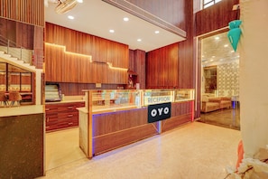 A reception area with a wooden reception desk, a staircase, and a reception sign. - HOTEL O SAFFRON (Meerut)