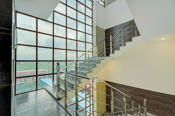 Un interior moderno con pared de vidrio, escalera y vistas al exterior.