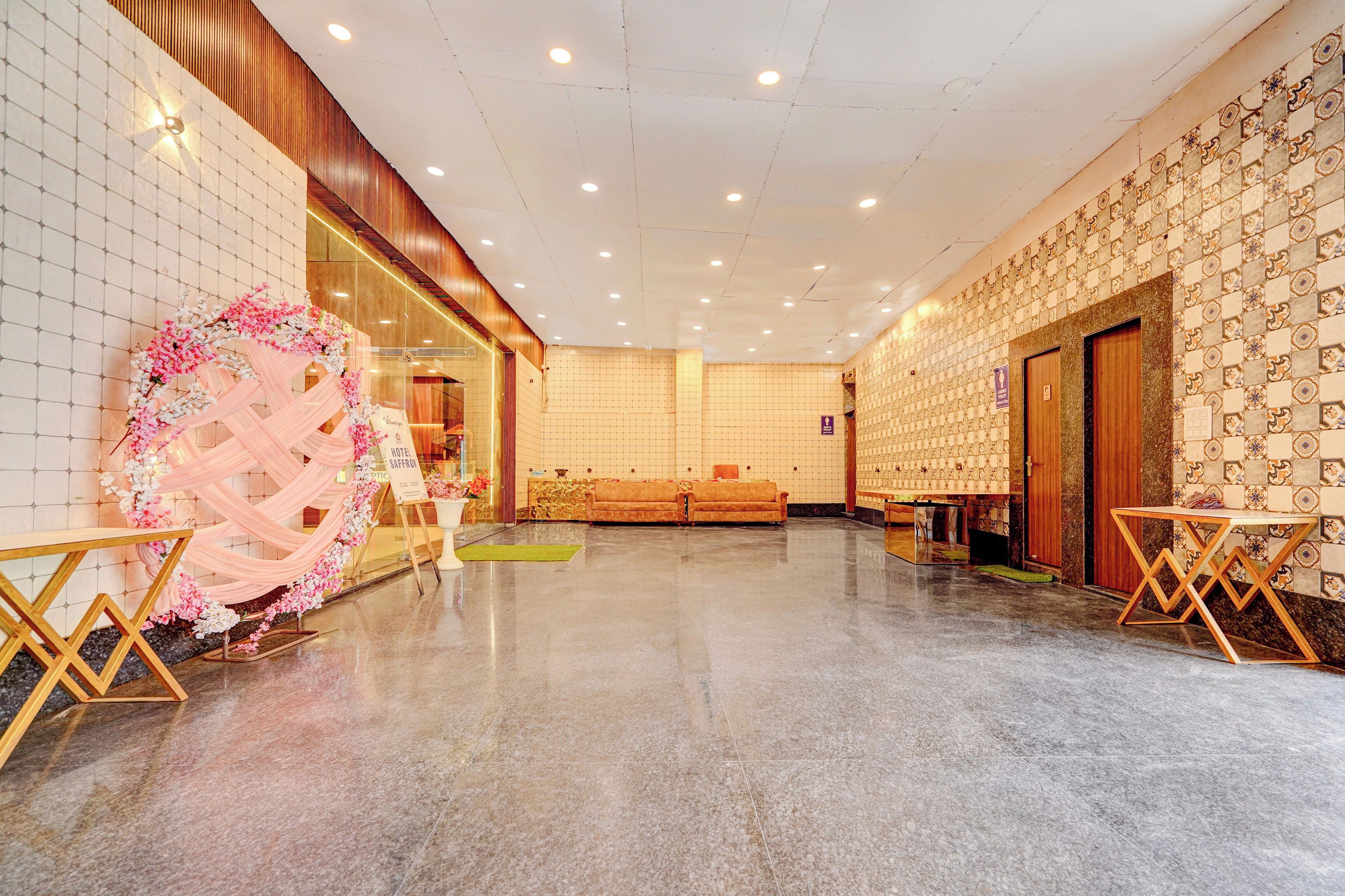 Un hall de hotel con una recepción, un sofá y un arreglo floral decorativo.